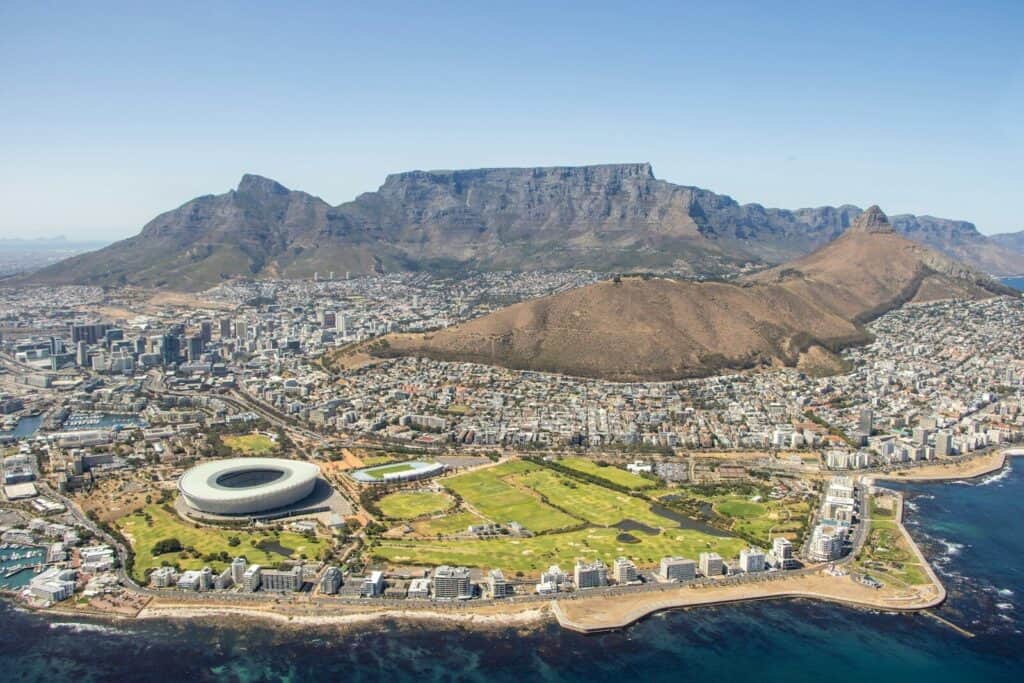 Aerial view of Cape Town with Table Mountain, the coastline, and city neighborhoods below.