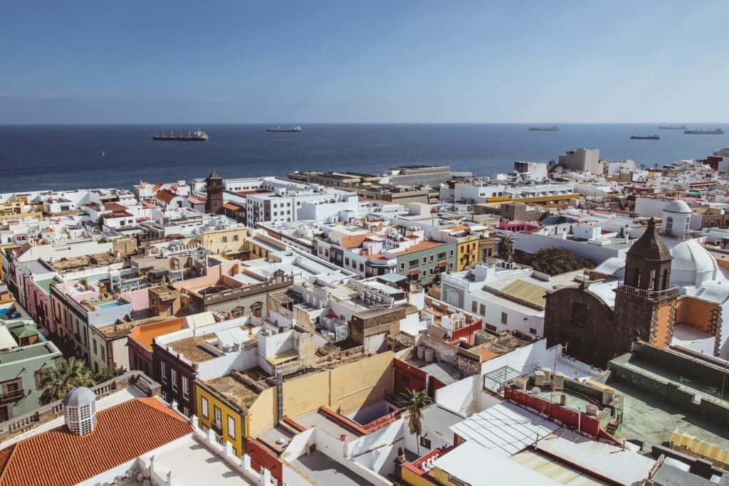View over Las Palmas with white rooftops, historic buildings, and the Atlantic Ocean in the background.