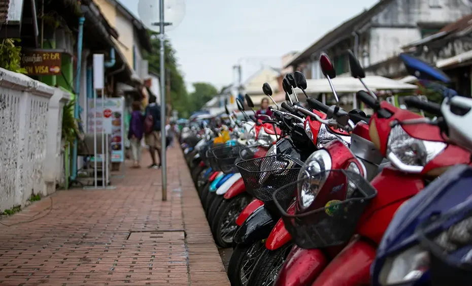 Row of scooters parked along a sidewalk in Thailand, used for a Chiang Mai scooter rental guide.