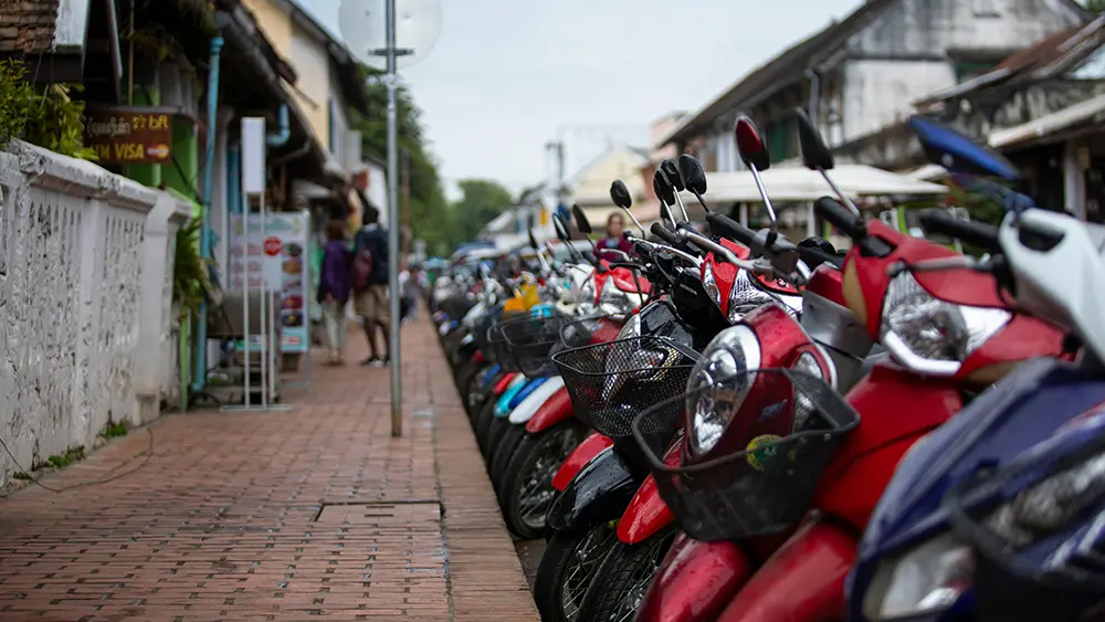 Row of scooters parked along a sidewalk in Thailand, used for a Chiang Mai scooter rental guide.
