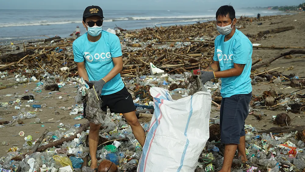 Two volunteers cleaning up trash on the beach in Bali.